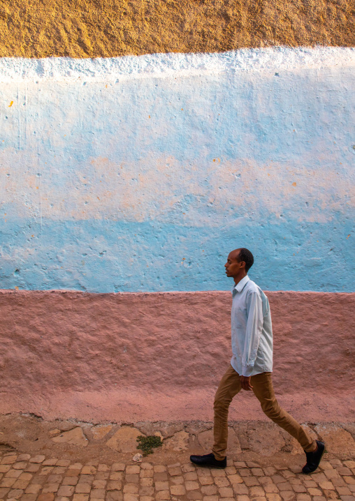 Ethiopian man passing along a wall in the old city, Harari region, Harar, Ethiopia