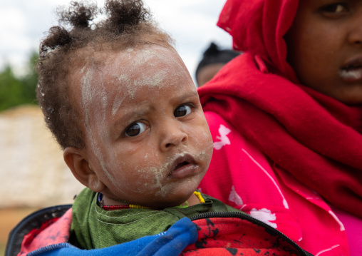 Oromo toddler with her mother in Sheikh Hussein shrine with jarawa powder on the face, Oromia, Sheik Hussein, Ethiopia