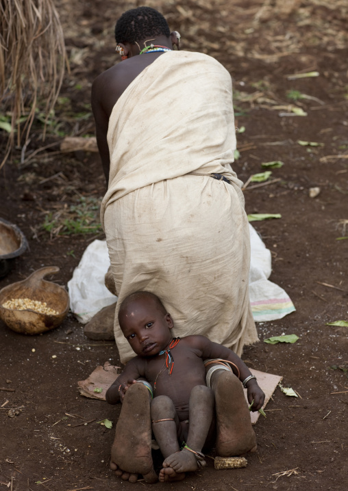 Young Suri Boy Sitting Between His Mother S Feet, Turgit Village, Omo Valley, Ethiopia