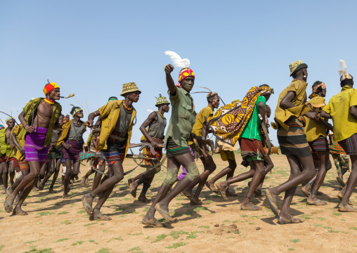 Men running in line with weapons during the proud ox ceremony in the Dassanech tribe, Turkana County, Omorate, Ethiopia