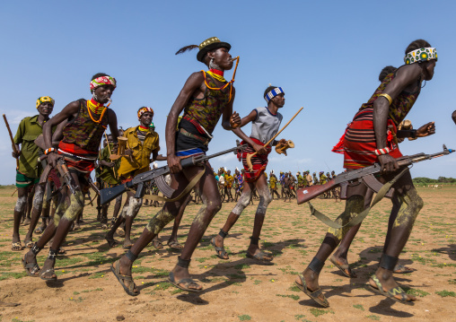 Men running in line with weapons during the proud ox ceremony in the Dassanech tribe, Turkana County, Omorate, Ethiopia
