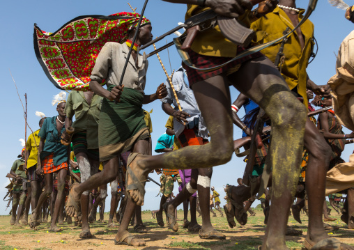 Men running in line with weapons during the proud ox ceremony in the Dassanech tribe, Turkana County, Omorate, Ethiopia