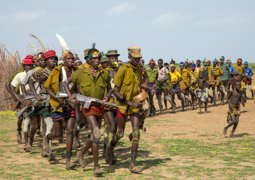 Men running in line with weapons during the proud ox ceremony in the Dassanech tribe, Turkana County, Omorate, Ethiopia