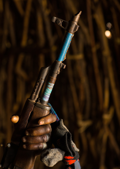 Nyangatom tribe woman holding a kalashnikov in her hut, Omo Valley, Kangate, Ethiopia