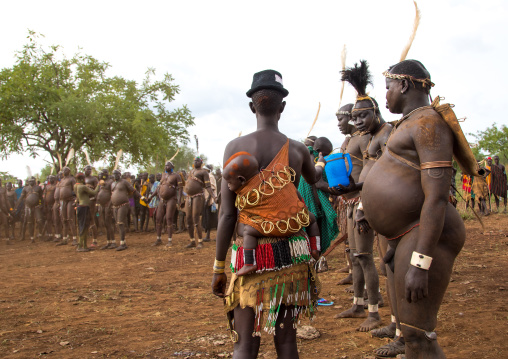 Woman giving milk to Bodi tribe fat men during Kael ceremony, Omo valley, Hana Mursi, Ethiopia