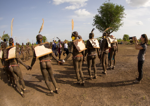 Tourist taking a picture of Bodi tribe fat men during Kael ceremony, Omo valley, Hana Mursi, Ethiopia