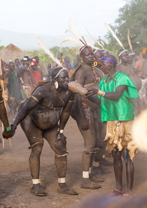 Woman giving milk to drink to a Bodi tribe fat man during Kael ceremony, Omo valley, Hana Mursi, Ethiopia