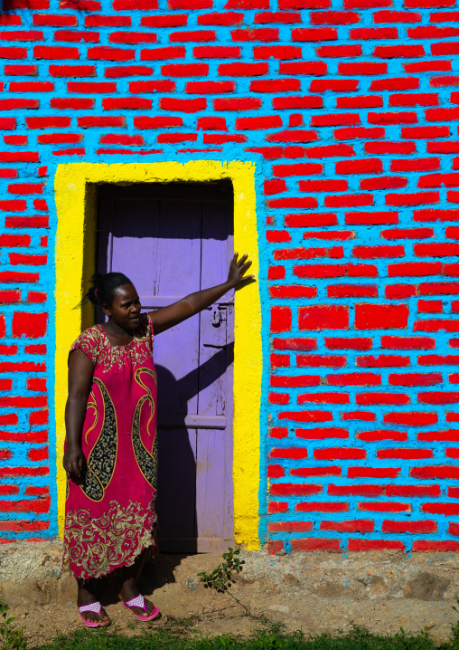 Ethiopian woman standing in front of colorful brick wall, Bench Maji, Mizan Teferi, Ethiopia