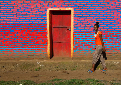 Ethiopian woman standing in front of colorful brick wall, Bench Maji, Mizan Teferi, Ethiopia