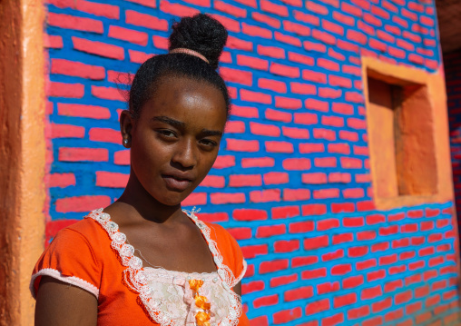 Ethiopian woman standing in front of colorful brick wall, Bench Maji, Mizan Teferi, Ethiopia