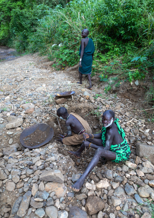 Suri tribe girls doing gold panning in a river, Omo valley, Kibish, Ethiopia