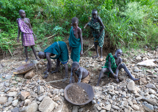 Suri tribe girls doing gold panning in a river, Omo valley, Kibish, Ethiopia