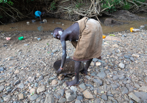 Suri tribe girl doing gold panning in a river, Omo valley, Kibish, Ethiopia