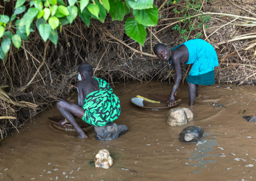 Suri tribe girls doing gold panning in a river, Omo valley, Kibish, Ethiopia