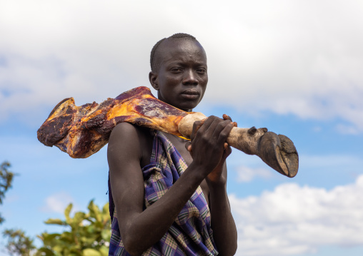 Suri man carrying meat on his shoulder, Omo valley, Kibish, Ethiopia
