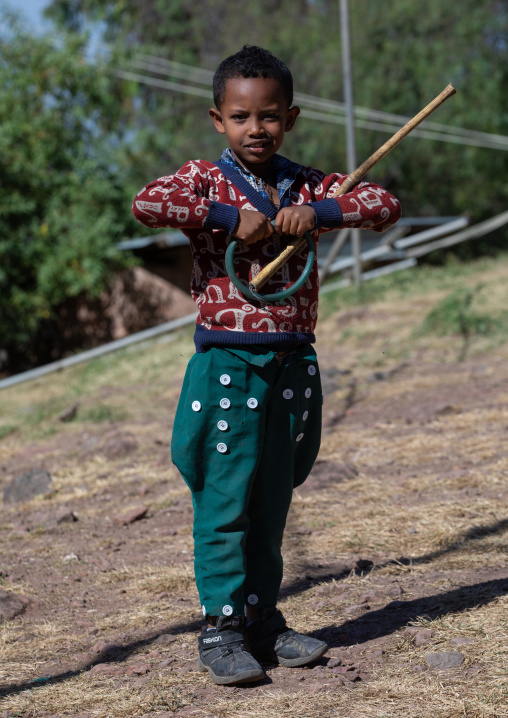 Amhara child with a green trouser with a lot of buttons as decoration, Amhara Region, Lalibela, Ethiopia