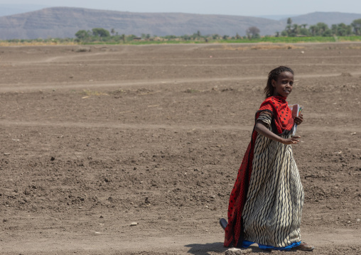 Afar tribe girl carrying books and going to school, Afar Region, Afambo, Ethiopia