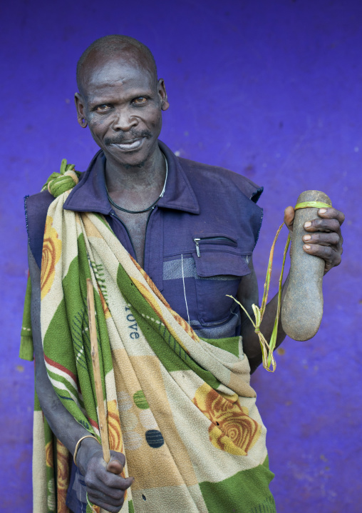 Suri tribe man holding a stone used to change the shape of cows horns, Kibish, Omo valley, Ethiopia