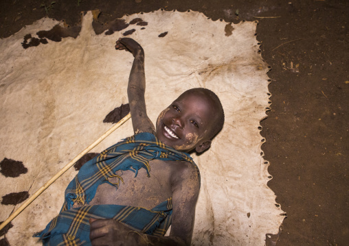 Bodi Tribe Kid Lying On A Cow Skin, Hana Mursi, Omo Valley, Ethiopia