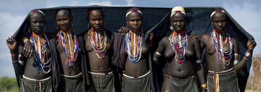 Young Arbore Tribe  Women With Beaded Jewels Pose Under Large Black Canvas, Omo Valley, Ethiopia