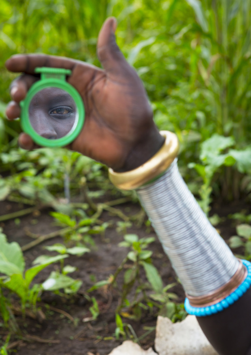 Suri tribe woman looking at herself in a mirror, Kibish, Omo valley, Ethiopia