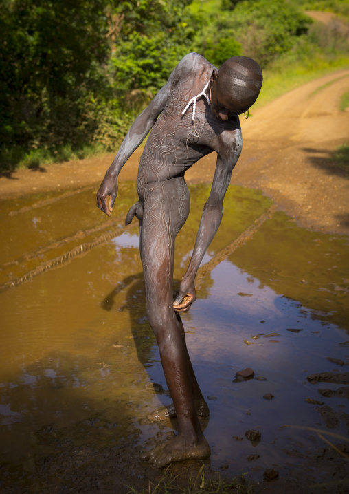 Shepherd from Suri tribe decorating his body with camouflage paintings, Tulgit, Omo valley, Ethiopia