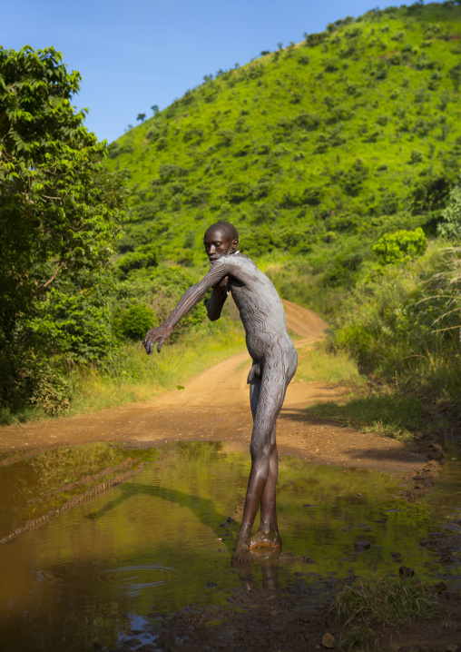 Shepherd from Suri tribe decorating his body with camouflage paintings, Tulgit, Omo valley, Ethiopia