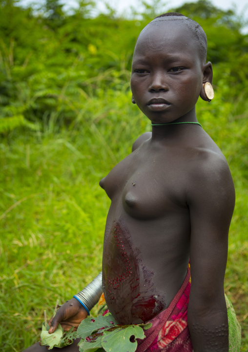 Suri tribe girl showing the scarifications on her belly covered by blood, Tulgit, Omo valley, Ethiopia