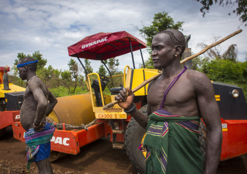 Bodi Tribe Warriors Posing Proudly Near A Bulldozer Near Hana Mursi, Omo Valley, Ethiopia
