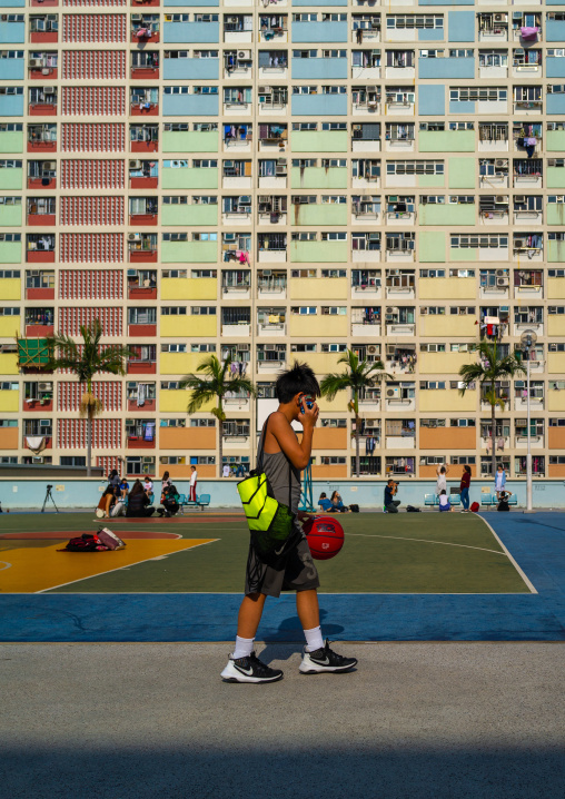 Chinese man speaking on his mobile phone in Choi Hung rainbow building, Kowloon, Hong Kong, China