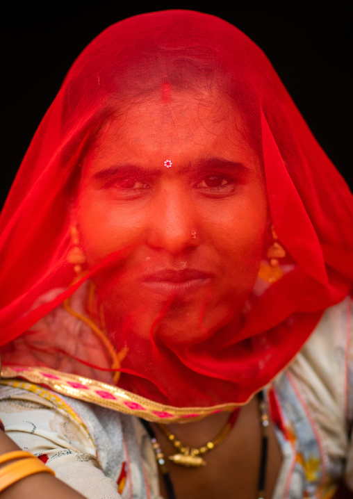 Portrait of a rajasthani woman hidding her face under a red sari, Rajasthan, Jaisalmer, India