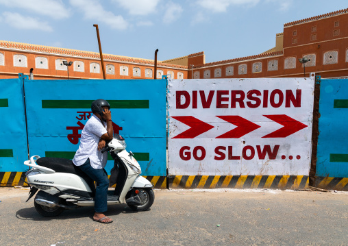 Indian man calling with his mobile phone on his scooter, Rajasthan, Jaipur, India