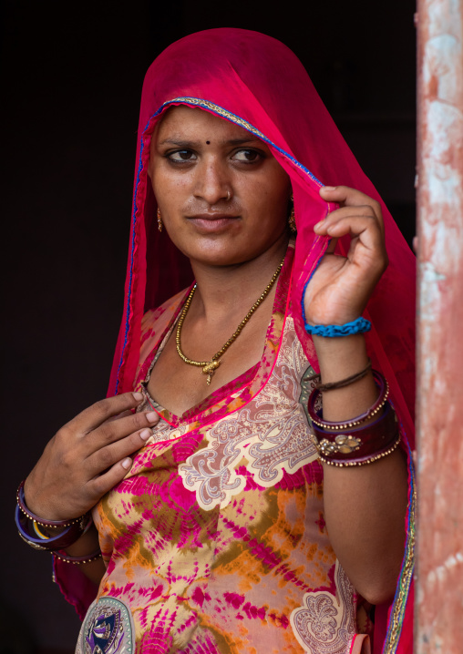 Portrait of a rajasthani woman hidding her face under a red sari, Rajasthan, Jaisalmer, India