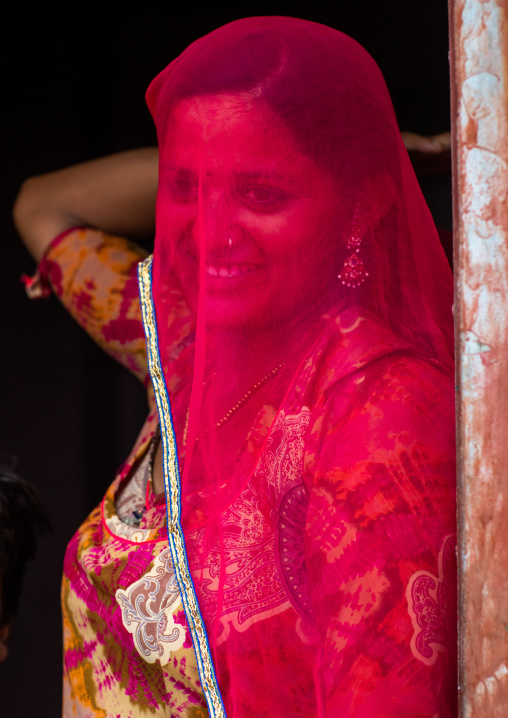 Portrait of a rajasthani woman hidding her face under a red sari, Rajasthan, Jaisalmer, India