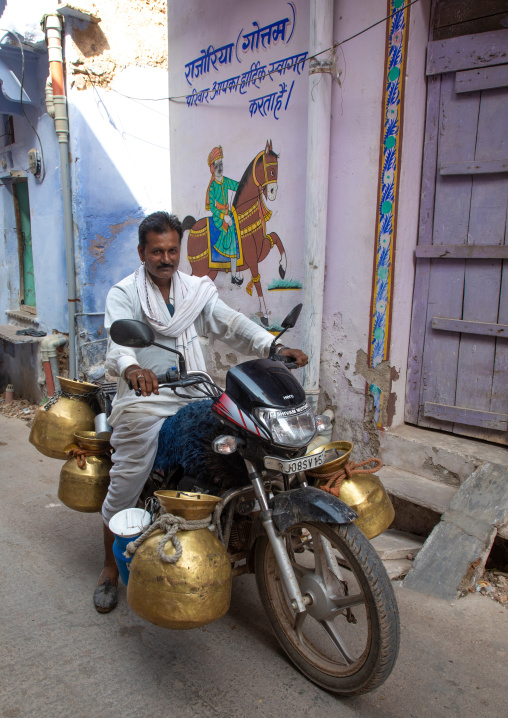 Indian man delivering fresh milk with his motorbike, Rajasthan, Bundi, India
