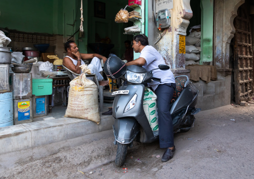 Indian man on a scooter speaking with a spices shop seller, Rajasthan, Jodhpur, India