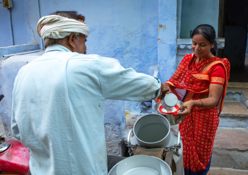 Indian man delivering fresh milk door to door with his motorbike, Rajasthan, Bundi, India