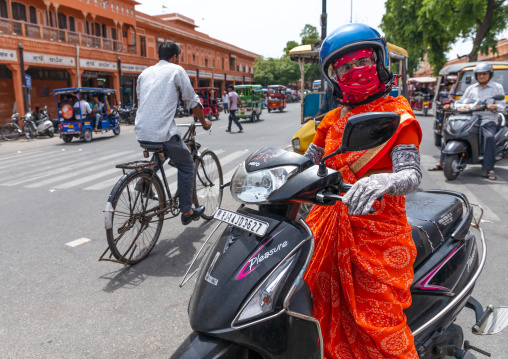 Indian woman in sari riding on scooter in the street, Rajasthan, Jaipur, India