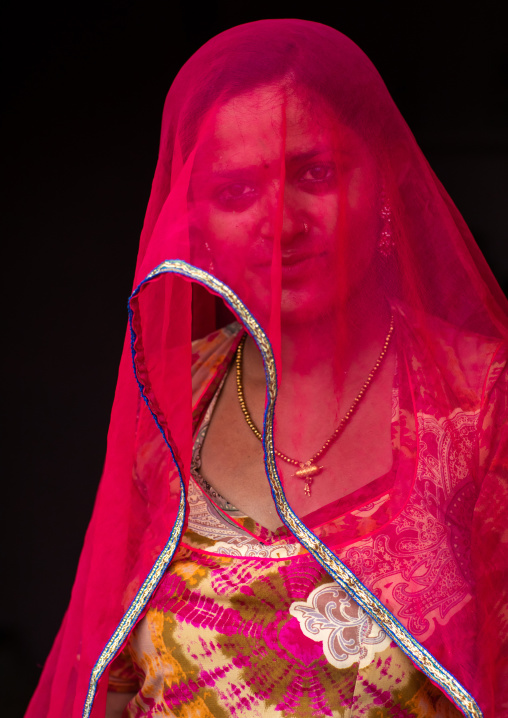 Portrait of a rajasthani woman hidding her face under a red sari, Rajasthan, Jaisalmer, India
