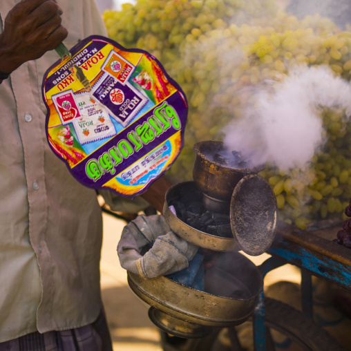Man Holding A Incence Burner In Front Of A Stall Of Grapes At Madurai Market, India