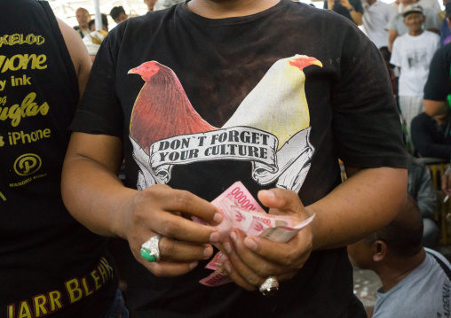 Men Taking The Money For The Bets During A Cockfigting Event