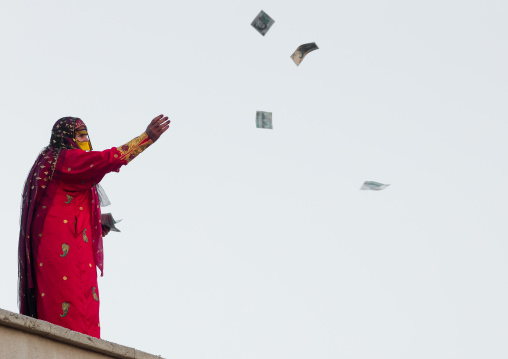women with face masks throwing bank notes to kids during a wedding, Hormozgan, Kushkenar, Iran