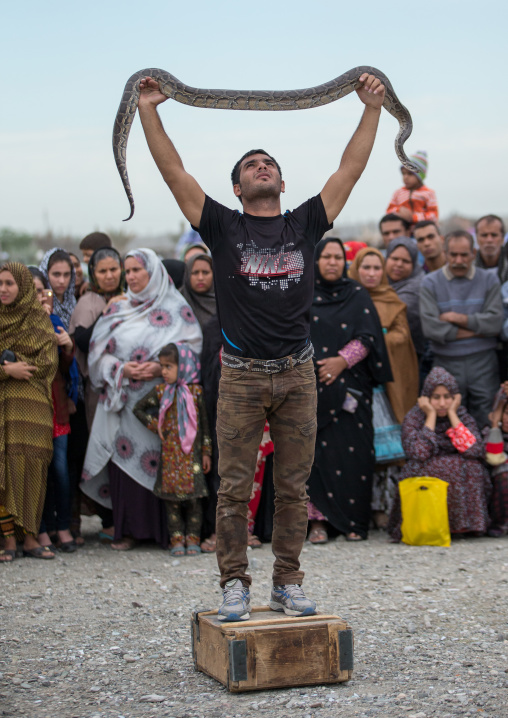 man showing a snake to the spectators during a show on a market, Hormozgan, Minab, Iran