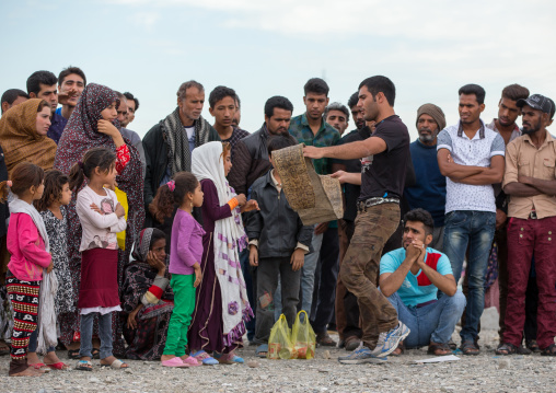 man showing a snake skin to the spectators during a show on a market, Hormozgan, Minab, Iran