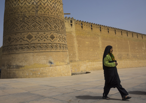 Woman passing in front of karim khan fort or arg e karim khan, Fars province, Shiraz, Iran