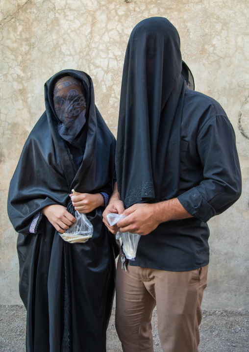 Portrait of iranian shiite muslim couple with their faces hidden by a veil mourning Imam Hussein on Tasua during the Chehel Manbar ceremony one day before Ashura, Lorestan Province, Khorramab