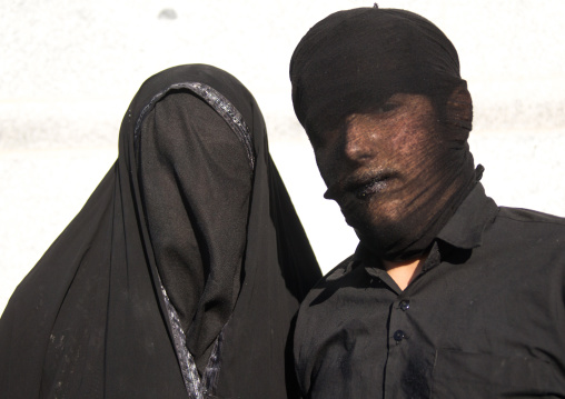 Portrait of iranian shiite muslim couple with their faces hidden by a veil mourning Imam Hussein on Tasua during the Chehel Manbar ceremony one day before Ashura, Lorestan Province, Khorramab