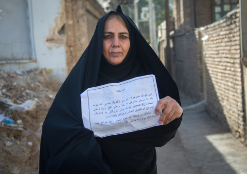 Old woman with a paper saying that thanks to Imam Hussein a child has been cured after she made a nazri during Muharram, Lorestan Province, Khorramabad, Iran