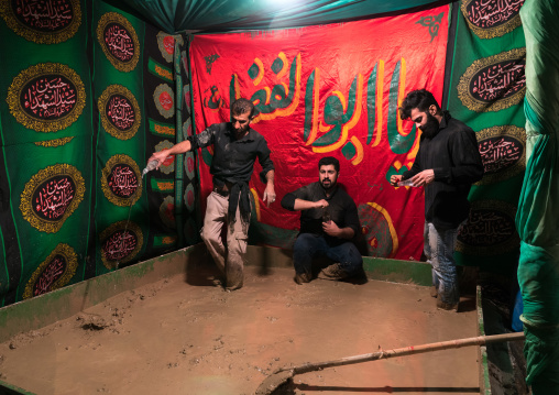 Iranian shiite muslim men prepare a mud pond for the Kharrah Mali ritual during the Ashura ceremony, Lorestan Province, Khorramabad, Iran