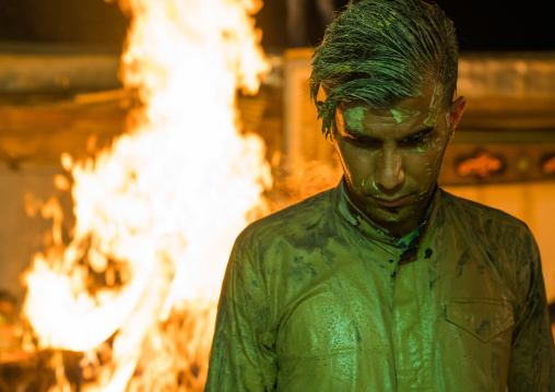 Iranian shiite muslim man standing in front of a bonfire after rubbing mud on his body during the Kharrah Mali ritual to mark the Ashura ceremony, Lorestan Province, Khorramabad, Iran